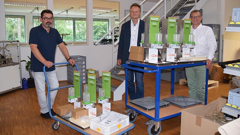 Abgeleitet von ihren Schmiermittelpumpen hat die Firma TriboServ in Geldersheim berührungslose Hand-Desinfektionsmittelspender entwickelt und gefertigt. Geschäftsführer Michael Weigand (Mitte) und Prokurist Gerhard Halbig (rechts) zeigen mit ihrem Mitarbeiter Stanislav Susak (links) die Spender.