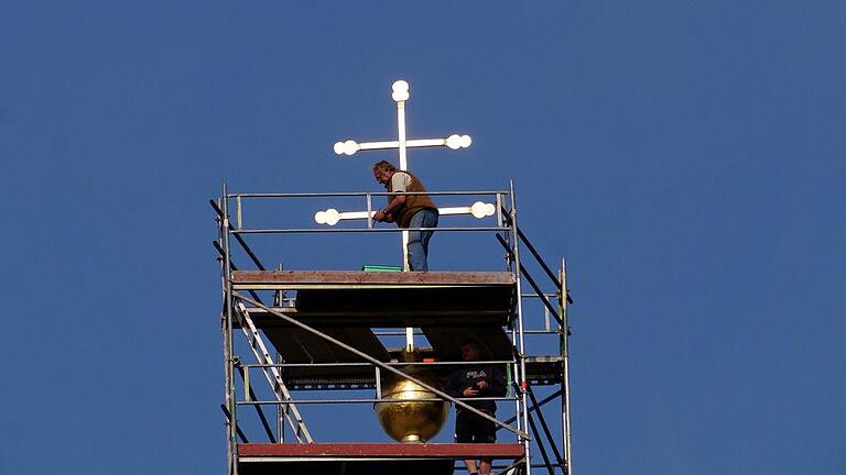 Es ist vollbracht: das Turmkreuz in der Fährbrücker Wallfahrtskirche ist an seinem Platz. Vergolder Bernhard Schmitt legt noch einmal Hand an und bessert kleinere Blessuren aus. Foto: Irene Konrad