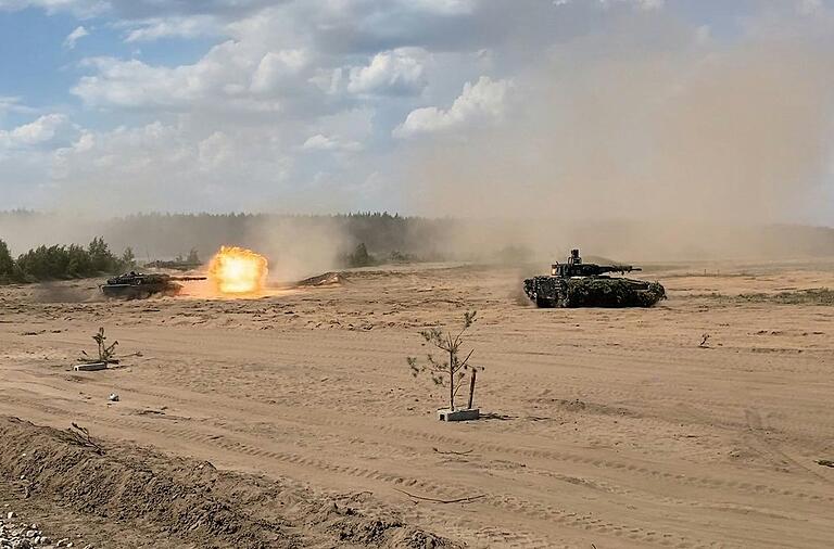 Ein Kampfpanzer der Bundeswehr vom Typ Leopard 2 feuert auf dem Truppenübungsplatz Pabrade in Litauen, rechts ein Schützenpanzer Puma.&nbsp;