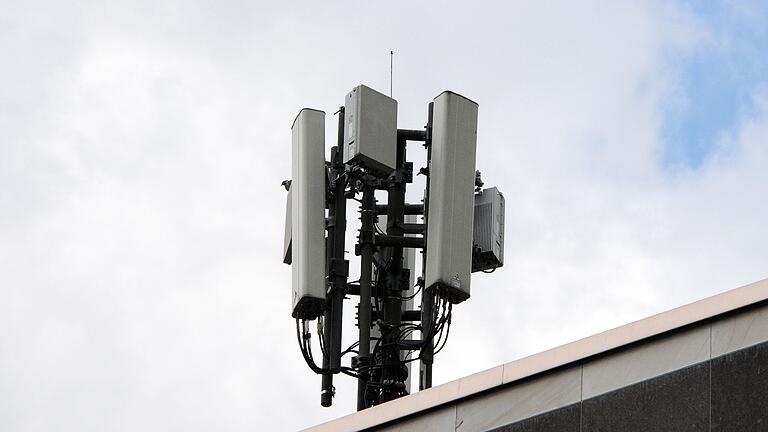 Mobilfunkantennen       -  Mobilfunkantennen des Funkstandards 4G (länglich) und 5G (quadratisch) sind auf einem Dach an einem kleinen Mast montiert.