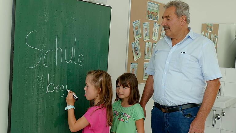 Die Schülerinnen Lenia und Malina probieren schon einmal die neue Tafel in der neuen Thüngener Grundschule aus. Bürgermeister Lorenz Strifsky schaut ihnen dabei über die Schulter.