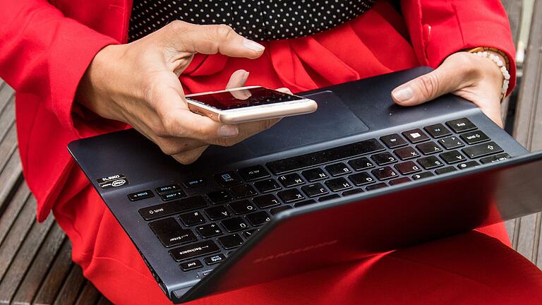 Frau mit Laptop und Smartphone       -  Sicherheit geht vor: Wer Whatsapp am PC nutzt, sollte zur aktuellen Version greifen – oder auf Whatsapp Web ausweichen.