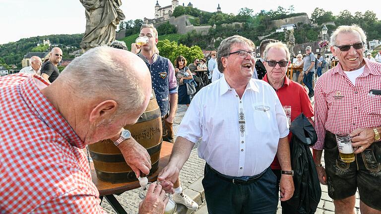 Der ehemalige Landrat Eberhard Nuß (links) zapft ein Glas für Würzburgs früheren Bürgermeister Adolf Bauer: Am Freitagabend gab es auf der Alten Mainbrücke einen kleinen Ersatz-Bieranstich zu Kiliani.