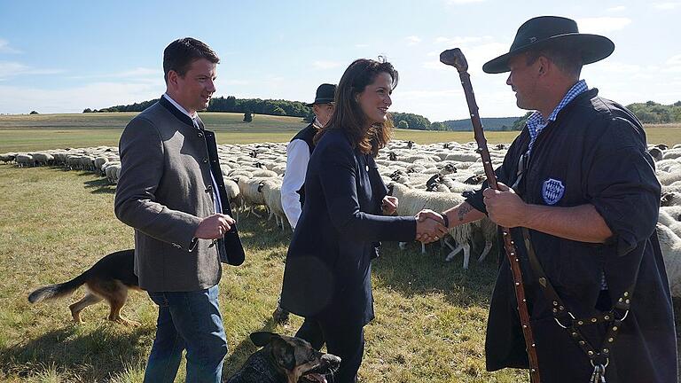 Die Bayerische Staatsministerin für Ernährung, Landwirtschaft und Forsten, Michaela Kaniber, begrüßt den Schäfer der Weidegemeinschaft, Julian Schulz, der mit über 1000 Rhönschafen derzeit auf der Weisbacher Jungviehweide unterwegs ist. Mit im Bild der Landtagsabgeordnete Sandro Kirchner (links), auf dessen Einladung die Ministerin in die Rhön kam.