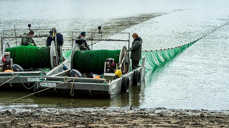 Die beiden Boote haben am Ufer angelegt. Mit einem Stahlseil wird das Netz über zwei Winden wieder eingeholt.