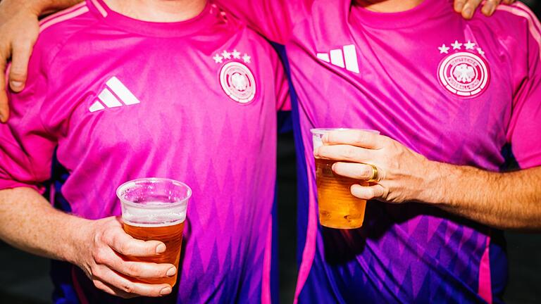 Zwei deutsche Fans trinken Bier       -  Volle Mägen und Alkohol erhöhen das Risiko: Beim Fußballschauen können Bratwurst und Bier die Herzbelastung erhöhen.