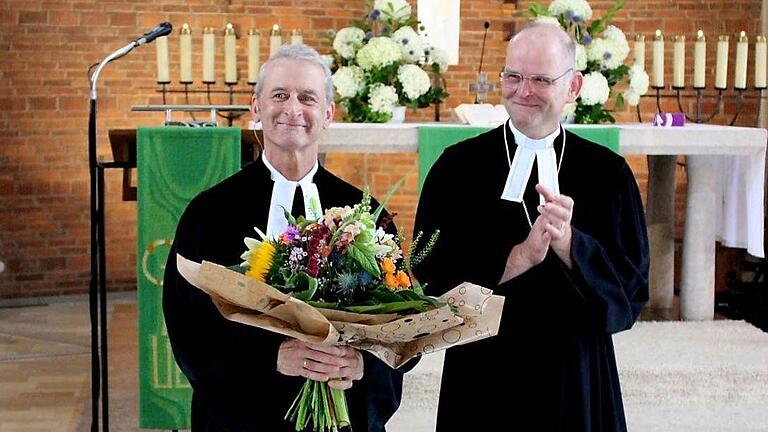 Pfarrer Harald Deininger (links) nach seiner Verabschiedung und Entpflichtung durch Dekan Oliver Bruckmann (rechts). Voller Dankbarkeit bedankte sich die versammelte Gemeinde mit stehenden Ovationen.