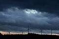 Windräder in Bayern       -  Windräder stehen bei Aitrang im Allgäu unter dichten Regenwolken hinter einem Wald.