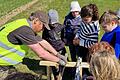 Schülerinnen und Schüler der Grundschule Gräfendorf beobachten einen Archäologen vom Landesamt für Denkmalpflege beim Untersuchen eines Bohrkerns im Lagfeld II.