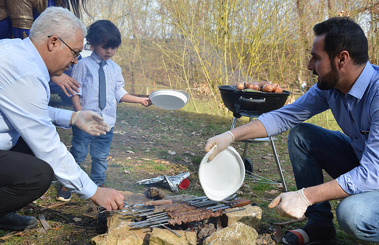 Luft fächelt auch schon der kleine Bub dem Feuer zu, damit Lamm- und Hähnchenspieße gelingen können. Links Shiar Ibrahim, der Organisator des kurdischen Neujahrsfestes. Luft fächelt auch schon der kleine Bub dem Feuer zu, damit Lamm- und Hähnchenspieße gelingen können. Links Shiar Ibrahim, der Organisator des kurdischen Neujahrsfestes.