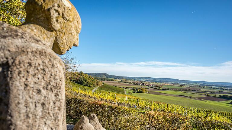 Unterwegs auf dem Wanderweg 'Ums Mahlholz' rund um Gerolzhofen: Am Alten Berg steht eine Statue des Heiligen Franziskus. Er hat den schönsten Platz hier oben, blickt über die Weinberge von Wiebelsberg, die Hangkante des Steigerwalds entlang. Links öffnet sich das Tal von Handthal mit seinen Weinbergen.