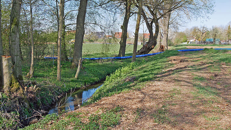 Noch liegt das blaue Rohr für das Fernwasser über dem Bergtheimer Dorfbach. Es wird in einem speziellen Bohrverfahren unter das Bachbett durchgespült.