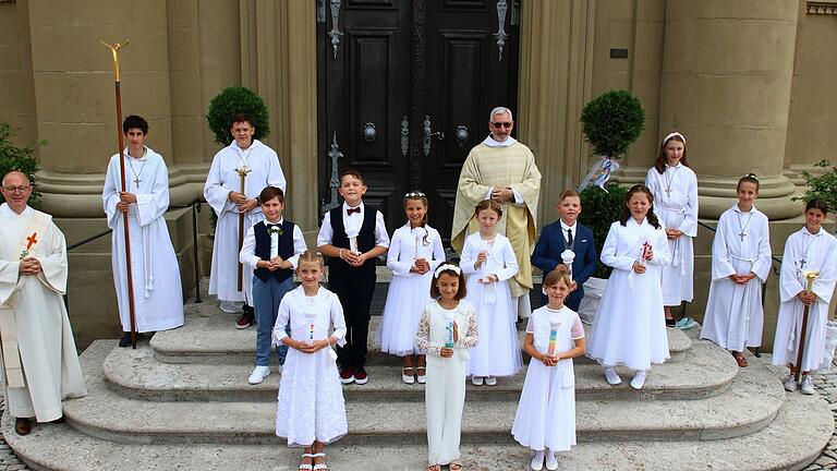 Zum Erinnerungsfoto mit Pater Philippus, Diakon  Uwe Rebitzer und den Ministranten vor dem Kirchenportal stellten sich die Kommunionkinder (hinten von links) Julius Trautmann, Rene Town, Leni Lechner, Clara Rosenbaum, Nick Oddoy (alle Wiesentheid), Nele Witte (Reupelsdorf), (vorne von links) Magdalena Henneberger (Wiesentheid), Margarete Reen, Mia-Sophie Schröder (beide Castell) auf.