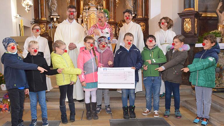 Die Kommunionkinder aus Lülsfeld, Frankenwinheim und Brünnstadt spendeten 780 Euro an den Verein Lachtränen e.V. also die Clowns, die sich um kranke Kinder und alte Menschen in Seniorenheimen kümmern. Hinter den roten Nasen sind die Kommunionkinder aus Lülsfeld und Frankenwinheim (vorne von links): Florentin Schmitt, Lenny Dülk, Katharina Böpple, Letizia Pfau, Amelie Weber, Anna-Lena Hasenkopf, Gustav Braum, Imma Haubenreich und Constantin Bauer. Es fehlen auf dem Foto: Adrian Lenhard, Jana Gebert und Mia Hofmann und aus Lülsfeld Carla Weisenseel, Jayden Kaiser und Lena Zinser. Hintere Reihe v. l. Ministrantin Rea Haubenreich, Pastoralassistent Florian Oberle, Clown Flora, Gottesdienstleiterin Stefanie Lembcke und Ministrantin Freja Haubenreich.