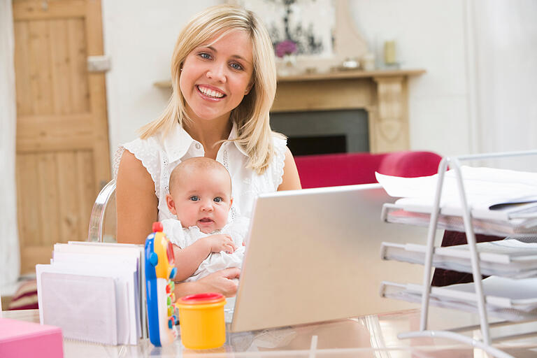 Ein Bild, das es so wohl nur gestellt gibt: Mutter, top gestylt, mit glücklichen Baby auf dem Schoß, arbeitet am Laptop.