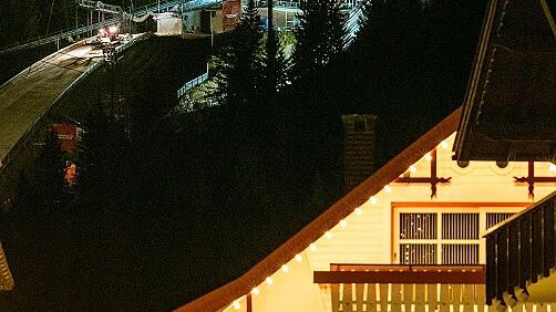 Vierschanzentournee Oberstdorf       -  Wenn es dunkel wird in diesen Tagen in Oberstdorf, schieben sich Massen an Besuchern durch die Fußgängerzone. Spektakulär dabei ist: Die beiden beleuchteten Skisprung-Schanzen sind zum Greifen nah.