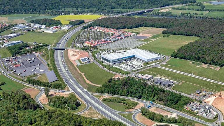 Blick auf das Gewerbegebiet 'Almosenberg' bei Wertheim-Bettingen (Aufnahme von 2018): In der Bildmitte die Erwin Hymer World, rechts oberhalb davon soll die geplante neue Warema-Produktionsstätte entstehen, und links unterhalb von Hymer wird das Warema Sun Forum gebaut. Im Hintergrund ist das 'Wertheim Village'.