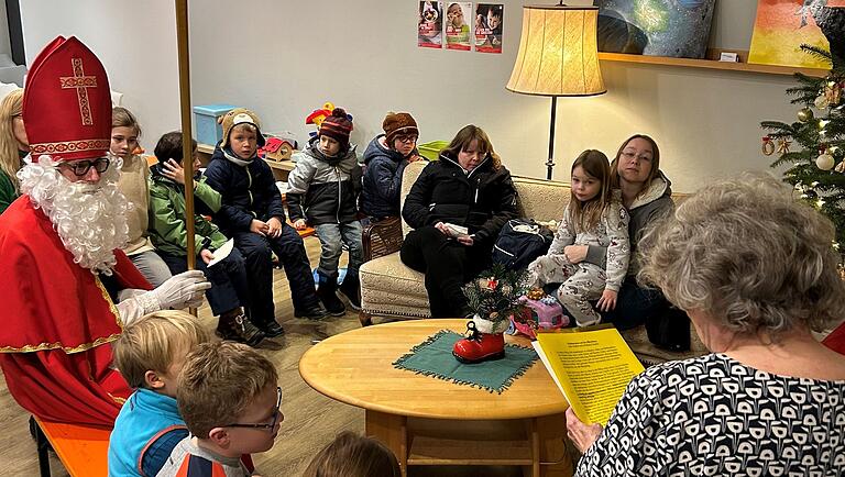 Der Nikolaus sitzt mit den Kindern um einen Tisch und lauscht der Weihnachtsgeschichte. Der Nikolaus sitzt mit den Kindern um einen Tisch und lauscht der Weihnachtsgeschichte.