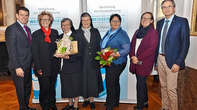 Viele Gratulanten umringen Sr. Eberharda (Dritte von links), die vom Freistaat mit dem &bdquo;Weißen Engel&ldquo; ausgezeichnet wurde: (von links) der Landtagsabgeordnete Steffen Vogel, die Geschäftsführerin des Caritasverbandes Rhön-Grabfeld, Angelika Ochs sowie (von rechts) Bürgermeister Eberhard Streit, die Pfarrgemeinderatsvorsitzende Gerda Staude, Johanna Dietz von der Sozialstation St. Kilian in Mellrichstadt und Sr. Meinrada Böhnlein.