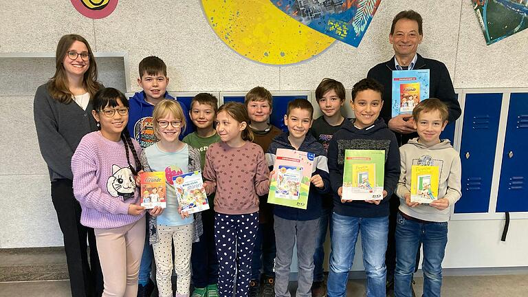 Jürgen Geisel, Rotary-Club Würzburg-Stein, überreicht die Büchergeschenke der Lehrkraft Christin Jacob und begeisterten Kindern der dritten Jahrgangsstufe.