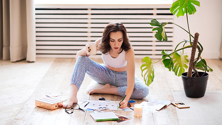 Young brunette woman creating her Feng Shue wish map using scissors       -  Selbst etwas Kreatives erschaffen geht auch mit Magneten.