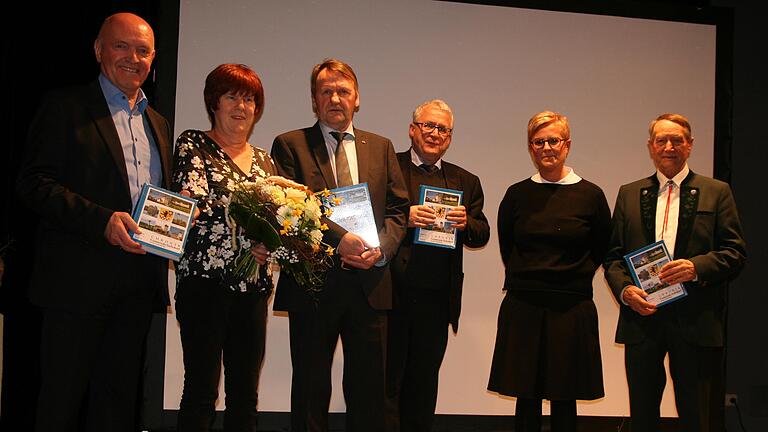 Bürgermeisterin Angelika Götz (Zweite von rechts) überreichte die Druckfrischen Exemplare des dritten Teils der Sulzdorfer Gemeindechronik an Landrat Thomas Habermann (links), Bezirksheimatpfleger Professor Klaus Reder (Dritter von rechts) und Altbürgermeister Lorenz Albert (rechts) und bedankte sich unter  großem Applaus der Gäste bei Marianne und Reinhold Albert für das gelungene Werk.