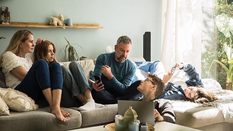 Eine Familie sitzt auf einem Sofa.jpeg       -  Full House auf dem Sofa: Mit vier oder mehr Kindern kann es in Deutschland eine vierstellige Summe an Kindergeld geben.