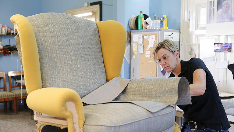 Kerstin Zorn bei der Arbeit: Der Ohrenbackensessel ist fast fertig. Zunächst wird der Stoff angeheftet, bevor er mit dem luftdruckbetriebenen Tacker&nbsp; befestigt wird. Foto: Johannes Kiefer