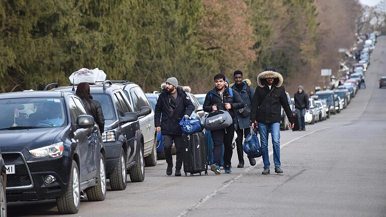 Nahe Lwiw sind Menschen neben der Autoschlange auf dem Weg zum Checkpoint Shehyni unterwegs, um die ukrainisch-polnische Grenze zu überqueren.