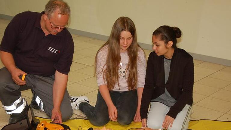 Burkard Kühn erklärt Emilia Kastl und Güller Babat die einzelnen Schritte zur Wiederbelebung.  Foto: Manfred Mellenthin       -  Burkard Kühn erklärt Emilia Kastl und Güller Babat die einzelnen Schritte zur Wiederbelebung.  Foto: Manfred Mellenthin