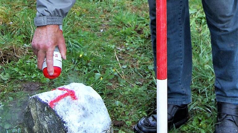 Ein Feldgeschworener zeichnet auf einen Grenzstein eine Markierung. - Ein Feldgeschworener zeichnet auf einen Grenzstein eine Markierung. Ein Feldgeschworener zeichnet auf einen Grenzstein eine Markierung. - Ein Feldgeschworener zeichnet auf einen Grenzstein eine Markierung.