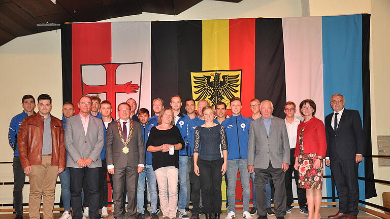 Das Foto zeigt alle Geehrten. Im Hintergrund die Aufstiegsmannschaft der SG Stadtlauringen-Ballingshausen sowie vorne (von links): Daimen Berger, Manfred Dietz, Bürgermeister Friedel Heckenlauer, Emma Bielefeldt-Müller, Lisa Heinrichs, Julian Müller, Helmut Böhm, Samuel Koch, stellvertretende Landrätin Bettina Bärmann und Bezirksrat Stefan Funk.