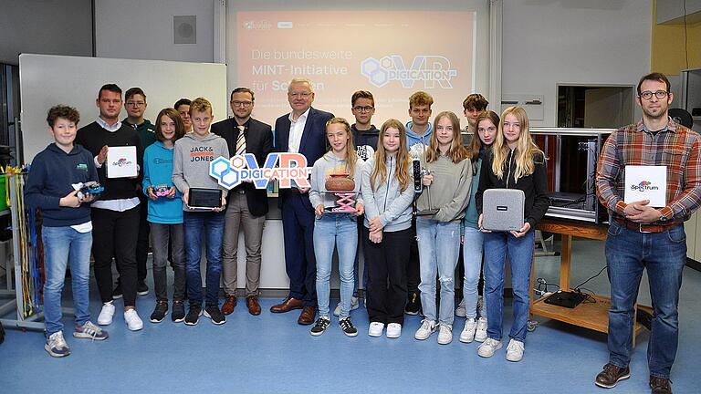 Das Bild zeigt die Spendenübergabe mit Schulleiter Sebastian Link (siebte Person von links), Volksbank-Vorstandsvorsitzendem Michael Schneider (achte Person von links), Ausbildungsleiter Tim Euler (zweite Person von links) und Physiklehrer Nicolas Betzel (rechts)