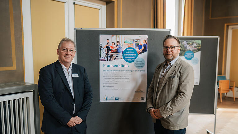 Von der Frankenklinik DRV Nordbayern: Chefarzt Dr. med. Christian Kuzman-Anton (l.) und Moritz Kaiser, Stellvertretender Kaufmännischer Leiter vor dem Poster der Frankenklinik
