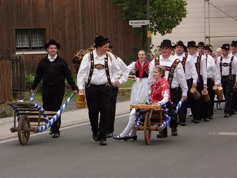 Im Festzug, begleitet von der Trachtenkapelle, marschiert die Kirmesjugend von der Kirche zum Dorfplatz. Die Trachten sorgen für einen festlichen Anblick.