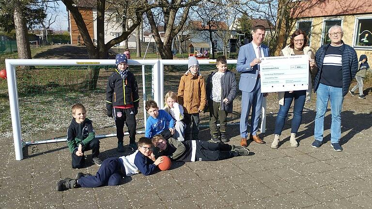 Das Foto zeigt die Schüler aus Großlangheim, die sich über die gesponserten Tore freuen, sowie (von links) den Geschäftsstellenleiter der Raiffeisenbank Mainschleife Steigerwald eG Bernd Braun, Rektorin Nicole Achter und Initiator Norbert Droll.