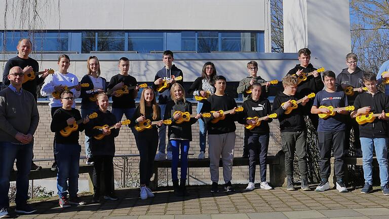 Gruppenbild der neuen Ukulelen-Klasse der Veitshöchheimer Mittelschule mit Musiklehrer Manfred Müller (hinten links) und den Sponsoren der Instrumente  (vorne v.l.) Fördervereinsvorsitzender Bruno Wnter und Elternbeiratsvorsitzender Marc Bertignoll, ganz rechts Rektorin Martha Winter