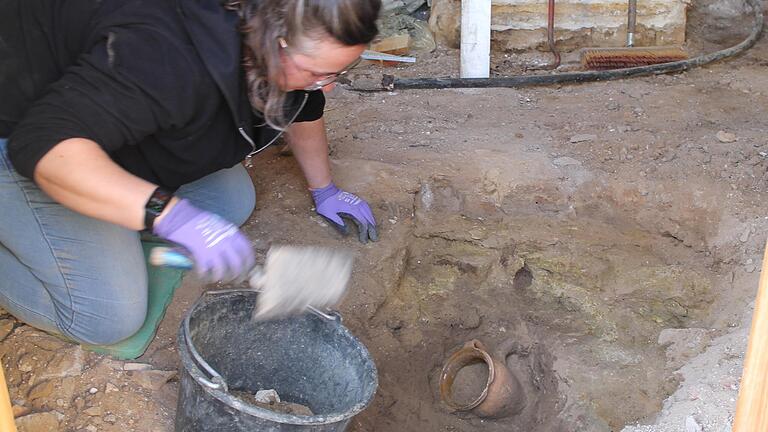 Unter losem Schutt und einer gestampften Lehmschicht lag der Nachgeburtstopf leicht schräg im Fußboden eines Bauernhauses in Brünnau. Grabungstechnikerin&nbsp;Sabrina Scherer holte das Artefakt in geduldiger Arbeit aus dem Erdreich.