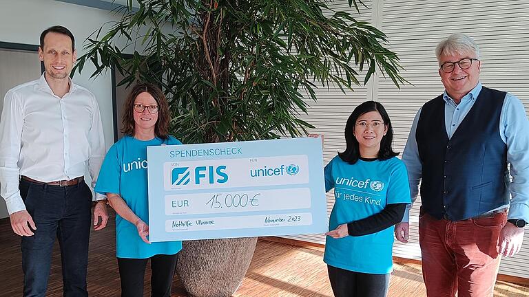 Vertreter der Firma FIS übergeben einen Spendenscheck in Höhe von 15.000 Euro an zwei Unicef-Vertreterinnen.