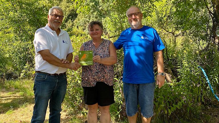 Das Bild zeigt links Klaus Sanzenbacher, LBV Kreisvorsitzender, die Gartenbesitzerin und Imkerin Agnes Ebert und Heinrich Wilhelm, LBV Kitzingen, bei der Übergabe der Auszeichnung 'Vogelfreundlicher Garten' in Volkach.