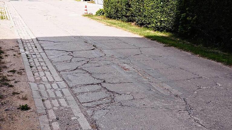 Die Straße &bdquo;Am Wasserturm&ldquo; hat Risse und Löcher. Die Gemeinde Bergtheim holt Angebote zur Erneuerung ein.