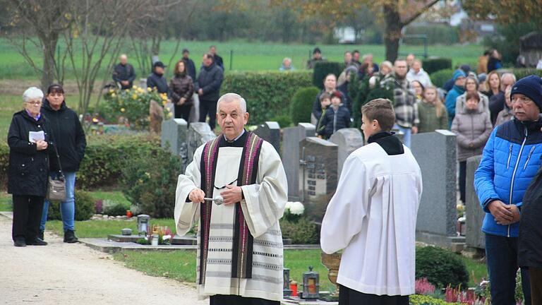 Während des ökumenischen Friedhofsgangs an Allerheiligen segnete Pfarrer Stefan Mai (Mitte) die Gräber auf dem Gerolzhöfer Friedhof.