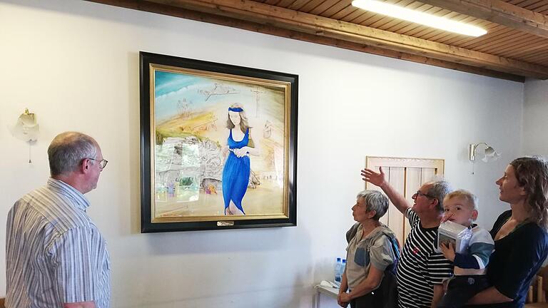 George Charbonnier erklärt Pater Markus Reis (links) seine Interpretation der  österlichen Szene mit seiner Figur der Maria Magdalena im Zentrum des Bildes. Auch seine Frau Christiane und Elisabeth Mehler mit Charbonniers Enkel Arthur  auf dem Arm hören ihm zu.Foto: Heike Beudert       -  George Charbonnier erklärt Pater Markus Reis (links) seine Interpretation der  österlichen Szene mit seiner Figur der Maria Magdalena im Zentrum des Bildes. Auch seine Frau Christiane und Elisabeth Mehler mit Charbonniers Enkel Arthur  auf dem Arm hören ihm zu.Foto: Heike Beudert