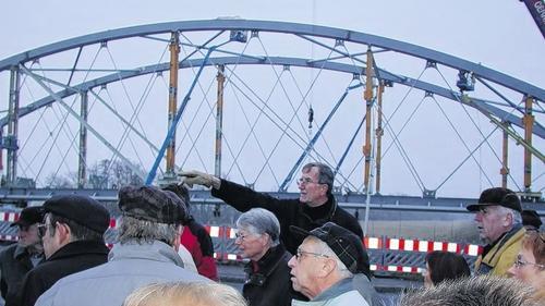 Trotz ungemütlichen Winterwetters wurde es den Neugierigen aus Grafenrheinfeld nicht kalt, die sich von Projektleiter Robert Haupt (Mitte) die Konstruktion der neuen Stahlbogenbrücke und das Einschwimmen des Bauteils auf die gegossenen Brückenpfeiler erklären ließen.