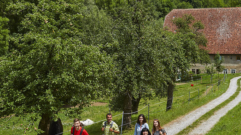 Wanderer im „Lieblichen Taubertal“ mit der Kulisse von Rothenburg ob der Tauber im Hintergrund.