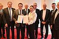 Die sieben Gesellschafter halten gemeinsam mit Notarin Natascha Both und dem Gründungsgeschäftsführer Tobias Wurm (links) den unterschriebenen Gesellschaftsvertrag in den Händen: Die Tourimia Tourismus GmbH ist gegründet.