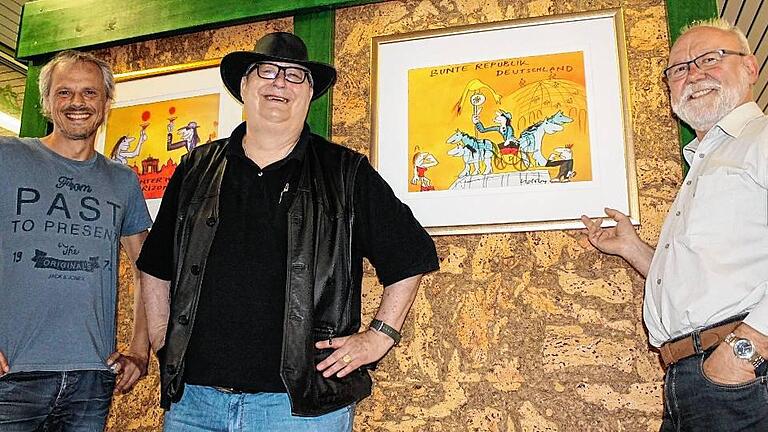 Die bunte Republik in der Mittelschule Mellrichstadt - (ski) Zwei echte Hingucker zieren neuerdings das Obergeschoss der Mittelschule Mellrichstadt: Karl-Hermann Reich (Mitte) hat der Schule Fotoreproduktionen von Udo-Lindenberg-Werken geschenkt. Die Originale der Bilder „Hinterm Horizont“ und „Bunte Republik Deutschland“ befinden sich im Besitz des ehemaligen Unternehmers, der selbst ein großer Fan des Altrockers ist. Zum Pressetermin kam er stilgerecht mit Hut. Was manch einer gar nicht weiß: In den 1990er-Jahren war Lindenberg auch als Maler in Erscheinung getreten, seine Werke fanden zunehmend Beachtung und hängen heute sogar im Bundeskanzleramt. Karl-Hermann Reich bewahrt diese Schätze in seinem „Kunstreich“ auf, wie er verrät. Ein drittes Bild mit dem Titel „Stark wie Zwei“, das Reichs Wohnzimmer ziert, will er der Schule ebenfalls noch zur Verfügung stellen. Sehr zur Freude von Schulleiter Egon Bauß (rechts) und Konrektor Achim Libischer (links), die sich bekanntlich Udo Lindenberg als Namensgeber für ihre Schule ausgeguckt haben. Bislang ruht allerdings das Verfahren, da der Panikrocker von der Staatsanwaltschaft Hamburg wegen unerlaubten Waffenbesitzes angeklagt wurde. Bei einer Kontrolle im November 2014 am Hamburger Flughafen war eine Waffe in Lindenbergs Gepäck entdeckt worden. Wann das Verfahren abgeschlossen ist, ist laut Egon Bauß, der diesbezüglich mit der Staatsanwaltschaft in Kontakt steht, ungewiss. Wird Lindenberg nicht verurteilt, darf sich die Mittelschule Mellrichstadt in Zukunft erste Udo-Lindenberg-Schule weltweit nennen. Dass man diesbezüglich recht zuversichtlich ist, zeigt sich beim Rundgang durch das Schulhaus. Überall zieren Bilder und Sprüche des mittlerweile 70-jährigen Rockers die Wände. „Keine Panik“ könnte sich alsbald zum Schulmotto herauskristallisieren. Foto: Simone Stock Die bunte Republik in der Mittelschule Mellrichstadt - (ski) Zwei echte Hingucker zieren neuerdings das Obergeschoss der Mittelschule Mellrichstadt: Karl-Hermann Reich (Mitte) hat der Schule Fotoreproduktionen von Udo-Lindenberg-Werken geschenkt. Die Originale der Bilder „Hinterm Horizont“ und „Bunte Republik Deutschland“ befinden sich im Besitz des ehemaligen Unternehmers, der selbst ein großer Fan des Altrockers ist. Zum Pressetermin kam er stilgerecht mit Hut. Was manch einer gar nicht weiß: In den 1990er-Jahren war Lindenberg auch als Maler in Erscheinung getreten, seine Werke fanden zunehmend Beachtung und hängen heute sogar im Bundeskanzleramt. Karl-Hermann Reich bewahrt diese Schätze in seinem „Kunstreich“ auf, wie er verrät. Ein drittes Bild mit dem Titel „Stark wie Zwei“, das Reichs Wohnzimmer ziert, will er der Schule ebenfalls noch zur Verfügung stellen. Sehr zur Freude von Schulleiter Egon Bauß (rechts) und Konrektor Achim Libischer (links), die sich bekanntlich Udo Lindenberg als Namensgeber für ihre Schule ausgeguckt haben. Bislang ruht allerdings das Verfahren, da der Panikrocker von der Staatsanwaltschaft Hamburg wegen unerlaubten Waffenbesitzes angeklagt wurde. Bei einer Kontrolle im November 2014 am Hamburger Flughafen war eine Waffe in Lindenbergs Gepäck entdeckt worden. Wann das Verfahren abgeschlossen ist, ist laut Egon Bauß, der diesbezüglich mit der Staatsanwaltschaft in Kontakt steht, ungewiss. Wird Lindenberg nicht verurteilt, darf sich die Mittelschule Mellrichstadt in Zukunft erste Udo-Lindenberg-Schule weltweit nennen. Dass man diesbezüglich recht zuversichtlich ist, zeigt sich beim Rundgang durch das Schulhaus. Überall zieren Bilder und Sprüche des mittlerweile 70-jährigen Rockers die Wände. „Keine Panik“ könnte sich alsbald zum Schulmotto herauskristallisieren. Foto: Simone Stock