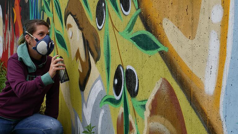 Die junge Frammersbacher Künstlerin Christine Dejok bei den letzten Arbeiten vor ihrem fast fertigen Graffitikunstwerk Lohr im Bibelgarten der evangelischen Kirche in Lohr. Die junge Frammersbacher Künstlerin Christine Dejok bei den letzten Arbeiten vor ihrem fast fertigen Graffitikunstwerk Lohr im Bibelgarten der evangelischen Kirche in Lohr.