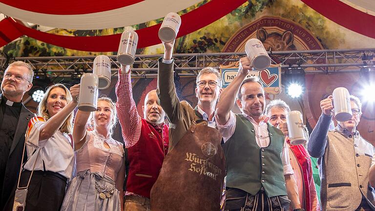 Oberbürgermeister Christian Schuchardt (mit Schürze) hält einen Bierkrug nach dem Fassanstich beim offiziellen Start des Kiliani-Volksfestes.&nbsp;