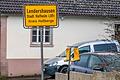 Ein Paar gelbe Gummistiefel hängt an einem Rechen neben dem Ortsschild von Lendershausen. Landwirtinnen und Landwirte bringen mit den Stiefeln aktuell ihren Protest zum Ausdruck.